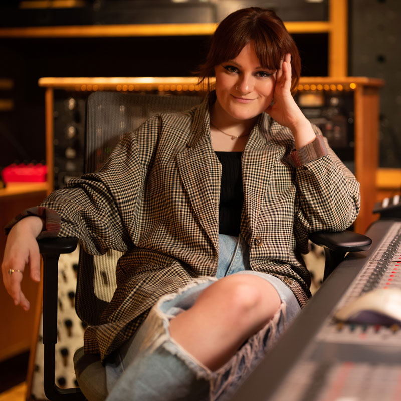 Beth Scott, who is sitting in a chair wearing jeans and a blazer